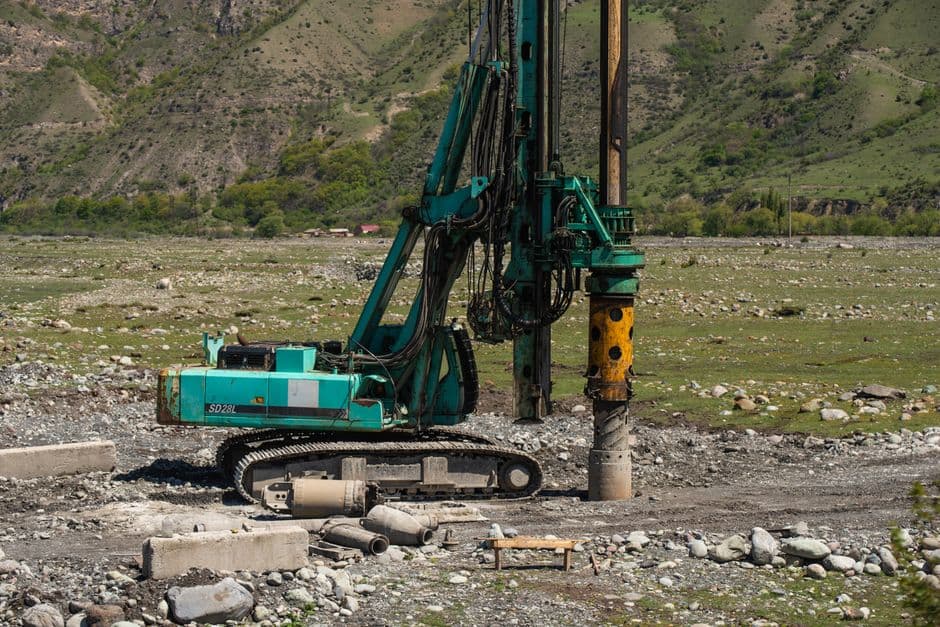 A heavy drilling machine in use on a rugged outdoor construction site.
